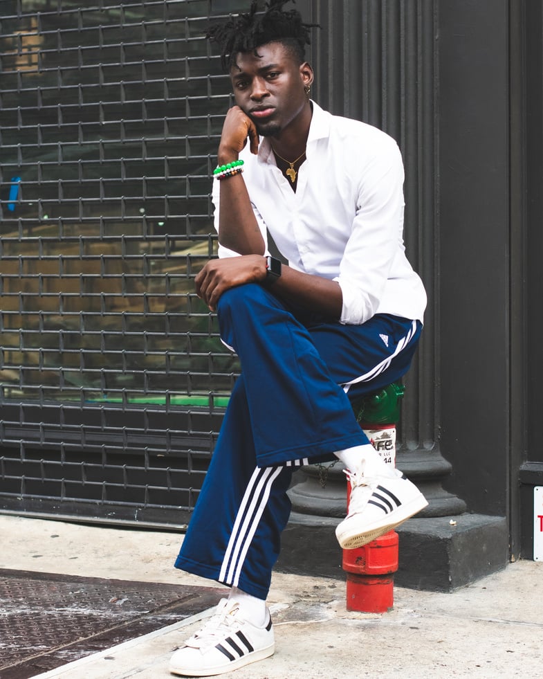 Man Wearing Blue Adidas Pants Sitting On A Post